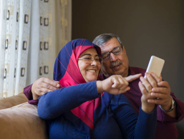 istock Senior couple using smartphone, having video call at home 1295415340