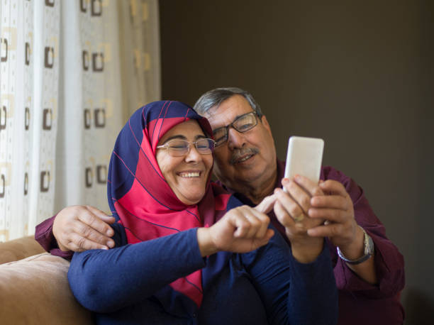istock Senior couple using smartphone, having video call at home 1295415346