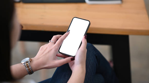 istock Close up view woman  hands holding smart phone with blank screen for your text message or information content. 1295420950
