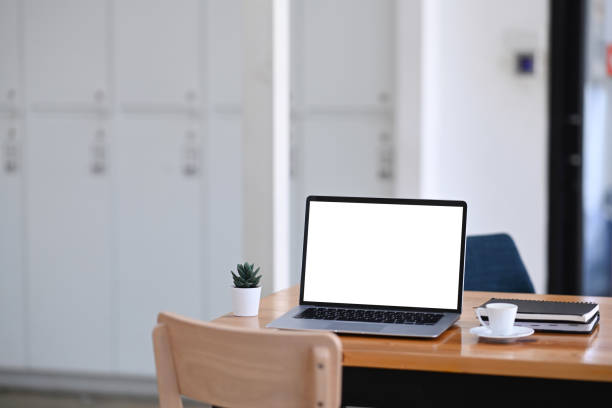 istock Mock up laptop computer with white screen on wooden table in modern office. 1295421811
