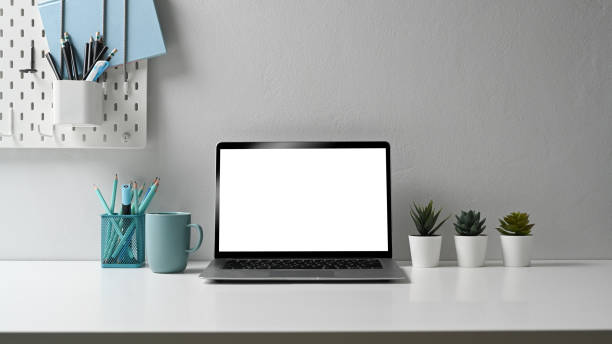 istock Stylish workstation with laptop computer, stationery, coffee cup and house plant on white table. 1295421881