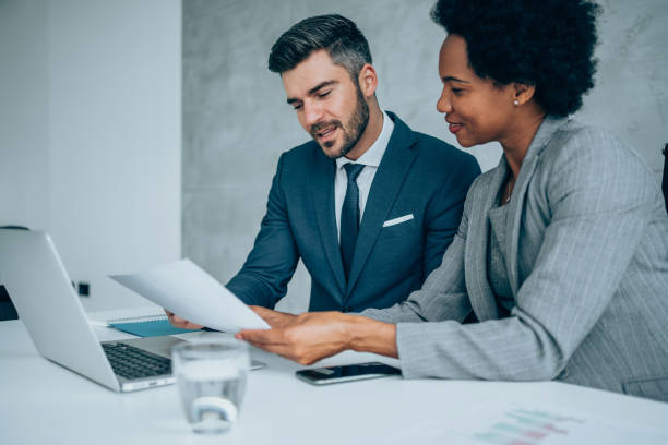 Business partners in meeting. Shot of two young business persons on meeting in the office. Two colleagues talking together while sitting in a modern office. Shot of businessman and businesswoman in meeting at the office. Business couple discussing important documentation in the board room. Two business people in office working on business reports. Business partners signing contract. african american business couple stock pictures, royalty-free photos & images