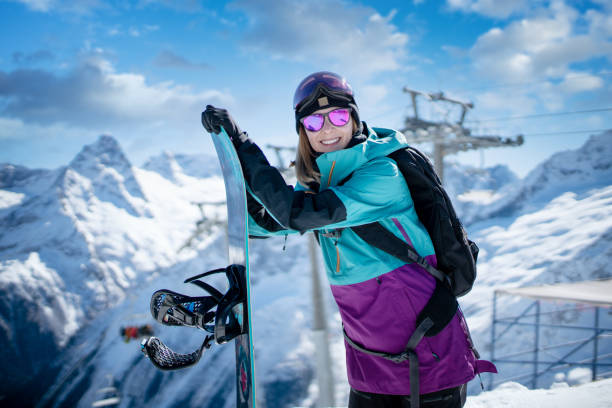 istock Smiling woman with snowboard standing at the slope 1295427522