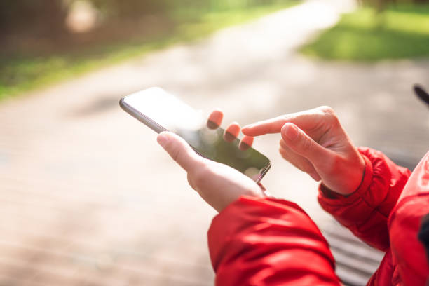 istock Woman uses smartphone while sits on a bench at public park 1295427599