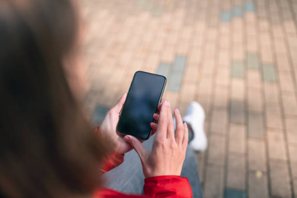 istock Woman uses smartphone while sits on a bench at public park 1295427617
