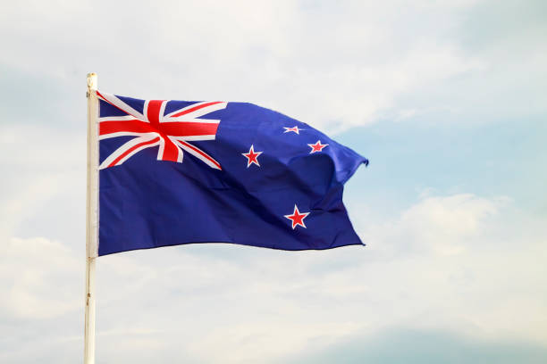 istock New Zealand flag on blue sky with clouds background 1295434557