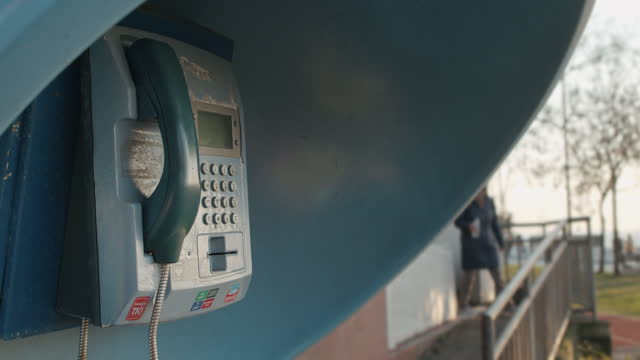 Nostalgic and Rusty Blue Pay Phone Booth has Left Alone in the Street Park in slowmo