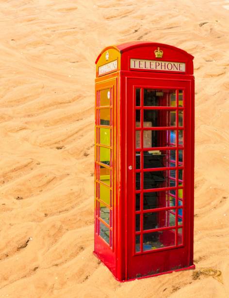 istock a red telephone booth stands on the sand 1295436306