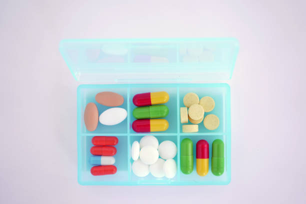 istock Many colorful tablets and capsules in a plastic box on a white background 1295436771