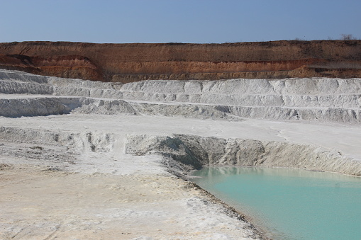 Clay mining. Beautiful background of white clay. Blue water