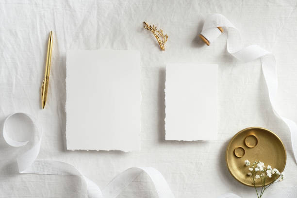 istock Beautiful wedding invitation cards template with golden decorations on white textile background top view. Romantic flat lay composition. 1295441580