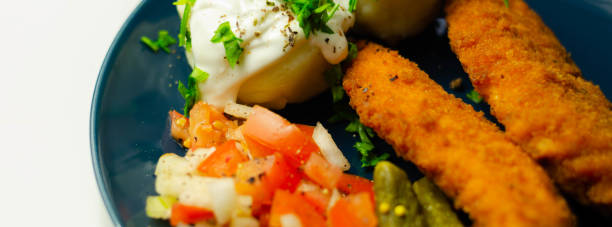 istock Breaded and herbed chicken breast fillet served with mashed potatoes,  tomato salad with onions and gherkin, 1295442944