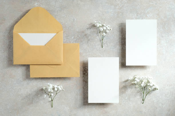Wedding stationery set on stone table top view. Flat lay blank invitation cards, envelopes, flowers.