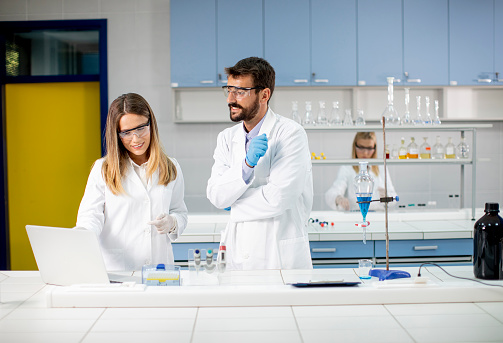 Researchers working with blue liquid at separatory funnel in the laboratory