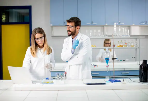 Photo of Researchers working with blue liquid at separatory funnel