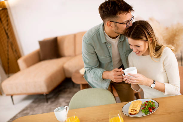 istock Happy couple having breakfast with sandwiches at table in kitchen 1295446539