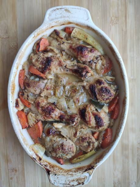 istock baked chicken legs with vegetables in onion beer sauce. 1295448334