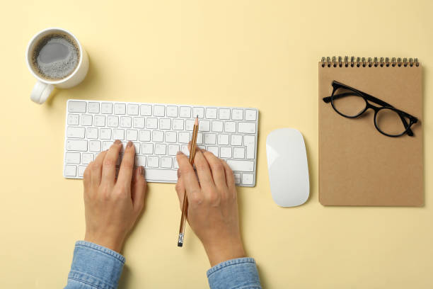 istock Woman working on modern keyboard on beige background 1295451815
