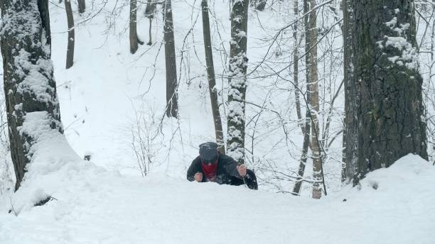 istock Man in red bandana using two knives climbs snow covered hill 1295452122