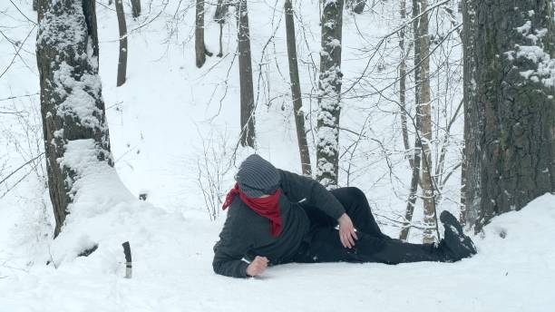 Man climber was injured in a hike, he lies and holds his leg Male climber lies on the snow and touches his injured leg. Knife sticks out of the snow nearby. The concept of dangerous, extreme tourism physical injury sport ice pain stock pictures, royalty-free photos & images