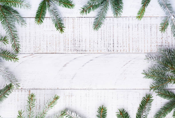 istock Christmas background with fir branches, pinecones, gift box, dried oranges, star anise and berries on the old white wooden board. Top view. 1295454817