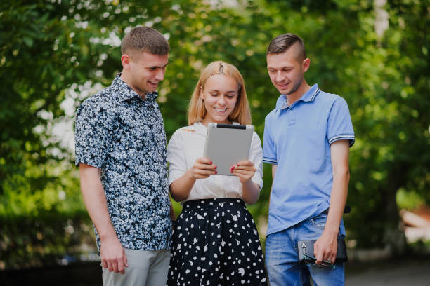 istock Three happy young people looking at digital tablet and smiling on green bacground 1295455058