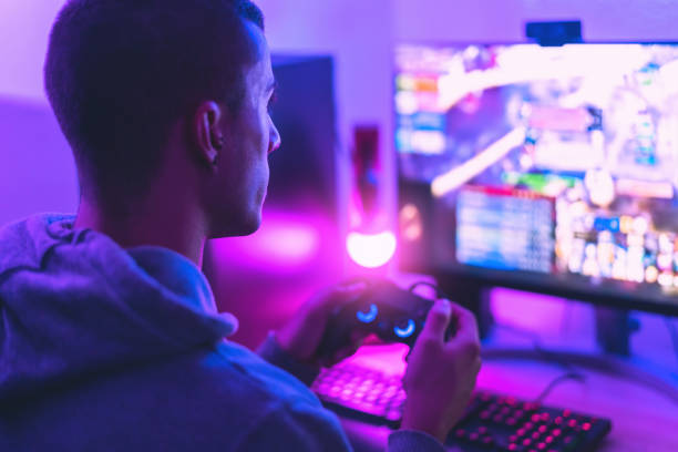 jugador joven jugando videojuegos en línea mientras transmite en las redes sociales - jóvenes adictos a los nuevos juegos de tecnología - videojuego fotografías e imágenes de stock