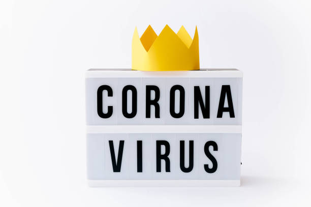 istock Covid 19, Corona virus text on display in lightbox with crown on it, light background. 1295470441