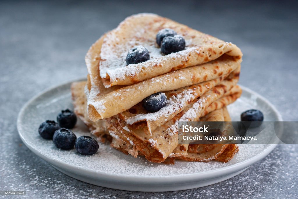 Crepes served with blueberries Homemade crepes served with blueberries and powdered sugar on small grey plate Crêpe - Pancake Stock Photo