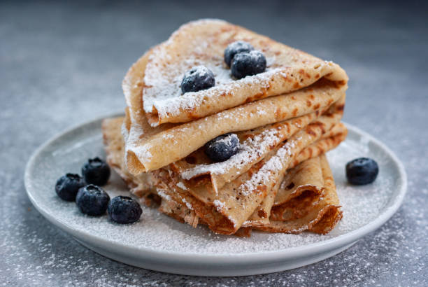 Crepes served with blueberries Homemade crepes served with blueberries and powdered sugar on small grey plate crêpe pancake photos stock pictures, royalty-free photos & images