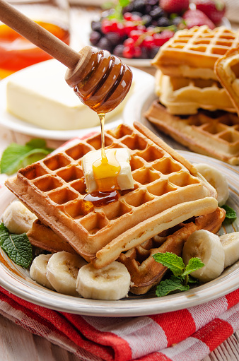 Belgian waffles served with butter banana mint leaf and syrup