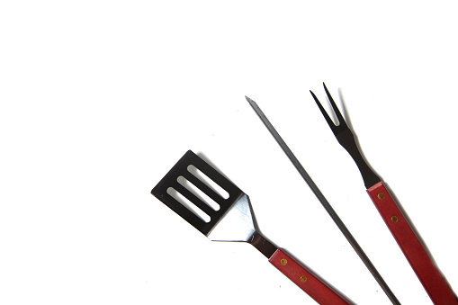 BBQ instruments kit - skewer, spatula, fork - close up isolated on white background flat lay. Image contains copy space