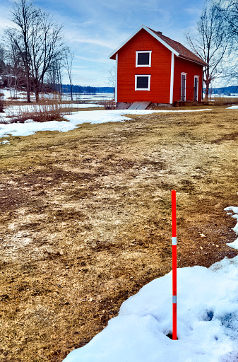Old red barn on field with melting snow. Spring approaches. The red stick marks the road when there is lots of snow.