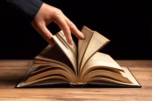 istock The man is shuffling the open book on the table. 1295481679