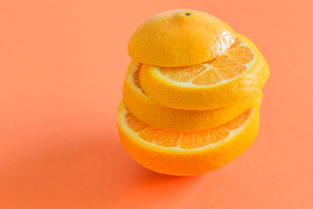 istock Fresh cut orange on the coral background.Fruit healthy diet. 1295481843