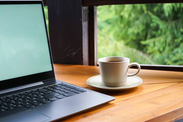 istock Laptop with a cup on a wooden table, close-up. Place for text 1295482231