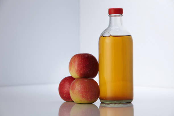 istock Bottle of apple cider vinegar and apples against white background 1295484319