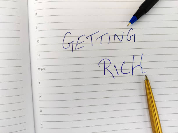 istock Selective focus of a Daily diary with text GETTING RICH and pen. 1295484609
