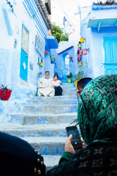 una mujer musulmana, con un hiyab, está tomando una foto de su familia en chefchaouen durante la pandemia de covid-19. - iphone 5 fotografías e imágenes de stock