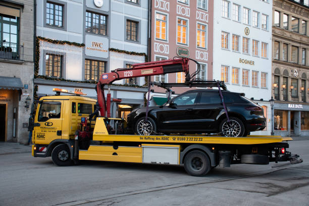 ADAC Truck Towing Luxury Car in Munich, Germany Munich, Germany - December 4, 2020: A vehicle of the ADAC (Europe's largest motoring association, headquartered in Munich) towing a luxury car in front of luxury designer stores in Max-Joseph-Platz in the city center. adac stock pictures, royalty-free photos & images