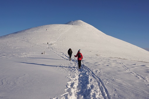 Pentland Hills, Scotland - 08 January 2021: Hikers and skiers are ascending the steep sides of West Kip through fresh snow. Taken during a lockdown period when Coronavirus restrictions had closed the country's ski centres.