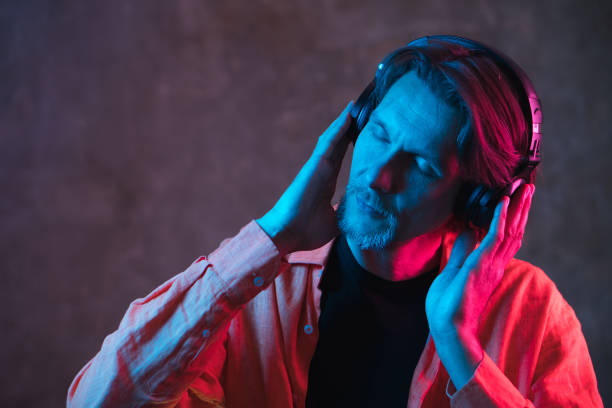 istock Attractive stylish man with colorful light on dark background. 1295496875