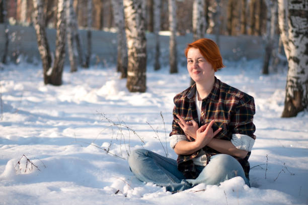 Beautiful young woman building a snowman outdoors in the wintertime.
