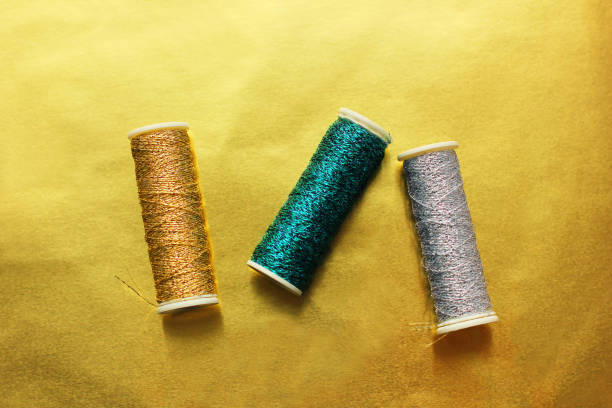 istock Sewing threads on a gold background. Bright shiny threads. Gold and white color. Trending colors 1295496915