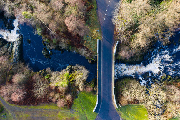 la vista de ángulo alto desde un dron mirando directamente hacia abajo hacia abajo en un puente que cruza una sección estrecha de agua de flujo rápido en dumfries y galloway al suroeste de escocia - europe high angle view waterfall water fotografías e imágenes de stock