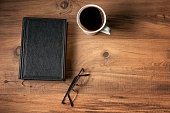 Black hardcover old book coffee and glasses on the table. top view