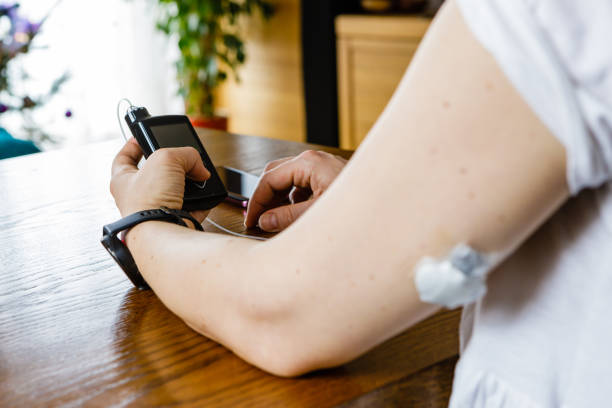 Modern diabetes treatment, woman checking glucose level and dosing insulin using insulin pump and remote sensor on her hand, focus on background
