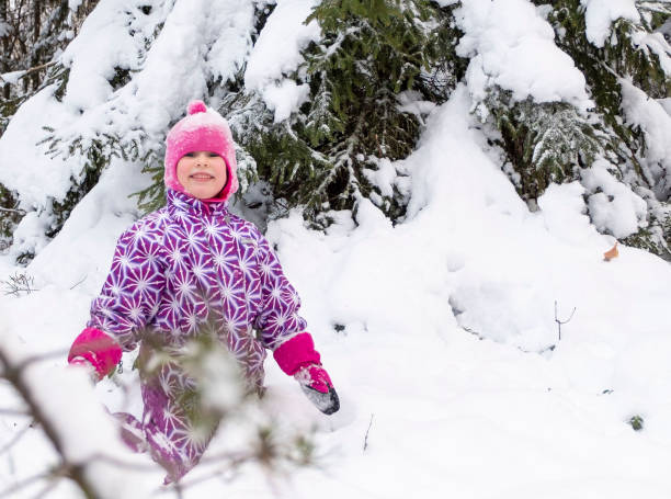 ein kind, ein 5-jähriges kaukasiermädchen, spielt fröhlich im tiefschnee. - child winter snow 4 5 years stock-fotos und bilder