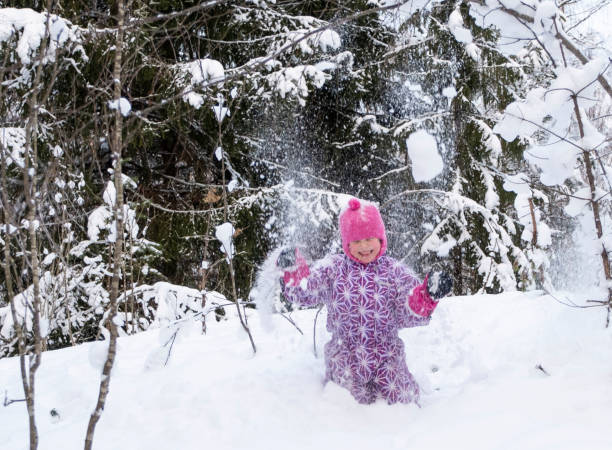 ein kind, ein mädchen 5 jahre alt kaukasier, duscht sich mit schnee. das mädchen hat spaß im winterwald. - child winter snow 4 5 years stock-fotos und bilder