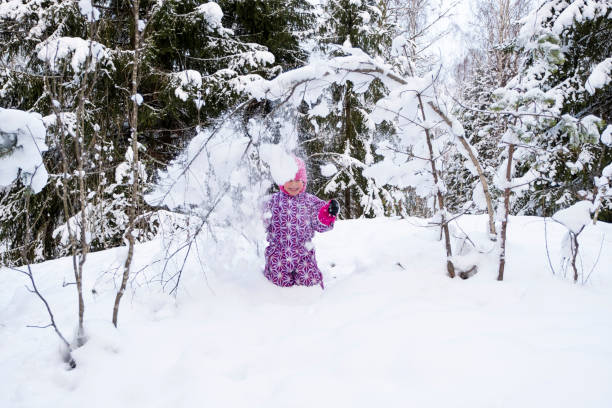 ein kind, ein mädchen 5 jahre alt kaukasier, duscht sich mit schnee. das mädchen hat spaß im winterwald. - child winter snow 4 5 years stock-fotos und bilder